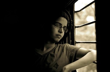 A person looks out a window in black and white image
